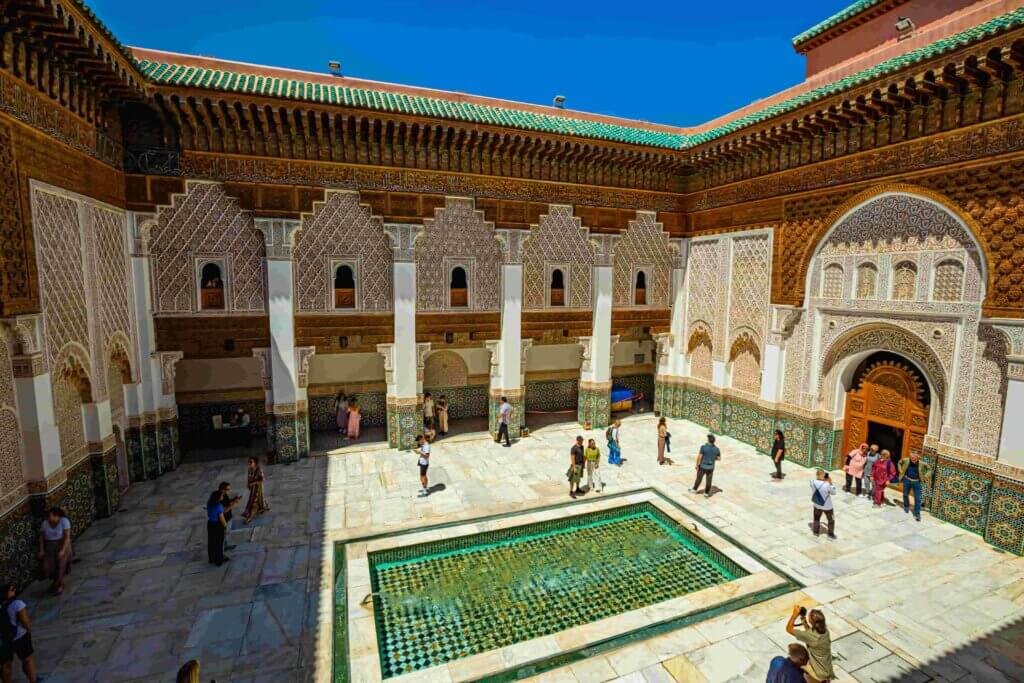 Un détail de zellige polychrome aux motifs géométriques étoilés orne un mur de la médersa Ben Youssef, illustrant la splendeur de l'architecture marocaine et le patrimoine mondial de Marrakech. Ces motifs complexes témoignent de l'artisanat traditionnel et de l'histoire de ce joyau de la médina.